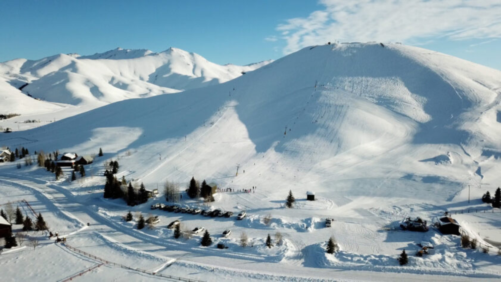 a snowy mountain with trees and a parking lot